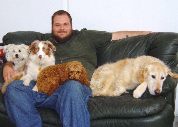 Erik seated with four dogs while working at Uppity Pup dog day care in Diamond Springs, California